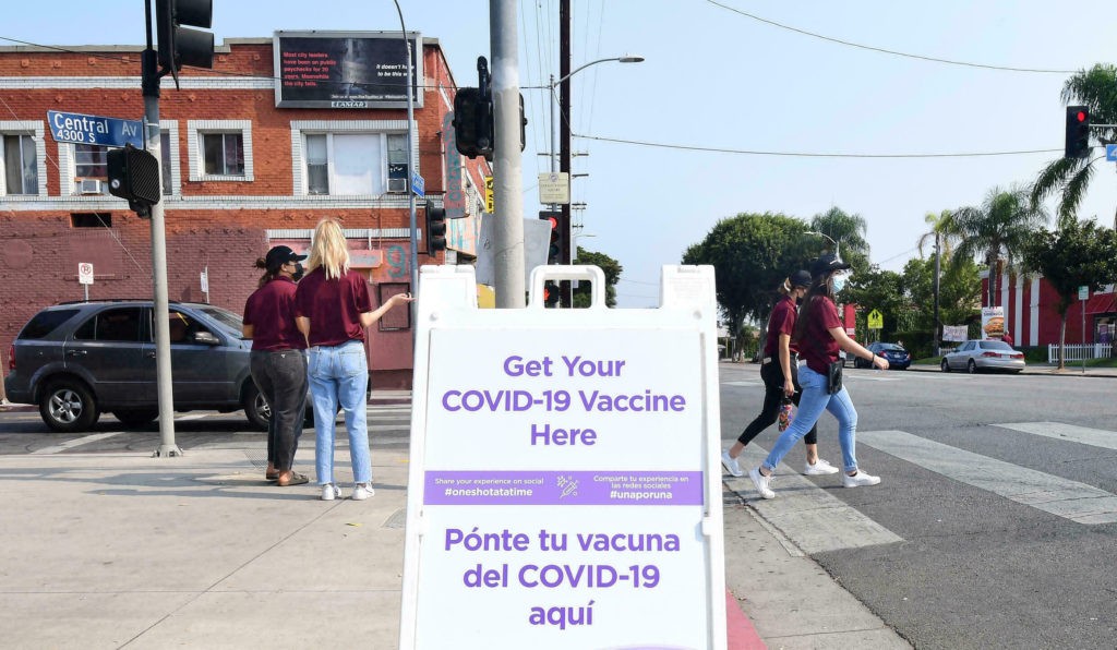 Volunteers in maroon shirts walk the neighborhood to let residents know about the Covid-19 vaccine location by AltaMed Health Services in Los Angeles, California on August 17, 2021. - LA County health officials will begin offering third doses of the Pfizer and Moderna Covid-19 vaccines for people with severely compromised immune systems this weekend. The CDC has revealed about 1.1 million people have already gotten a third dose of the Pfizer or Moderna vaccines on their own, although it remains unclear how many did so due to their weakened immune systems. (Photo by Frederic J. BROWN / AFP) (Photo by FREDERIC J. BROWN/AFP via Getty Images)