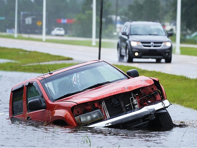 An abandoned vehicle is half submerged in a ditch next to a near flooded highway as the outer bands of Hurricane Ida arrive Sunday, Aug. 29, 2021, in Bay Saint Louis, Miss. (AP Photo/Steve Helber)