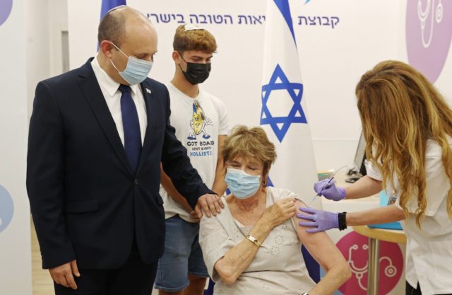 Israeli Prime Minister Naftali Bennett accompanies his mother Myrna as she receives a thir