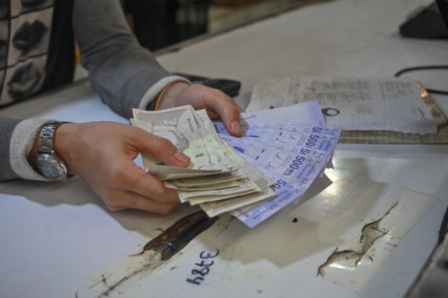 A man counts out bolivar banknotes in the Catia market in Caracas ahead of Venezuela's latest redenomination of the currency