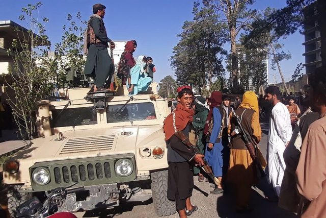 Taliban fighters stand on a vehicle along the roadside in Herat, Afghanistan's third bigge