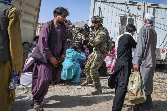 A US soldier (C) points his gun towards an Afghan passenger at the airport in Kabul, where chaotic scenes unfolded after the Taliban took over the country