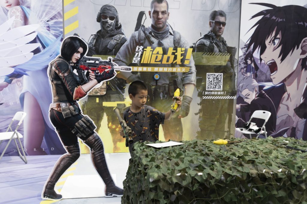 A child plays with a toy gun during a promotion for online games in Beijing on Saturday, Aug. 29, 2020. China is banning children from playing online games for more than three hours a week, the harshest restriction so far on the game industry as Chinese regulators continue cracking down on the technology sector. (AP Photo/Ng Han Guan)