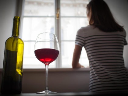 Woman drinking wine alone in the dark room - stock photo