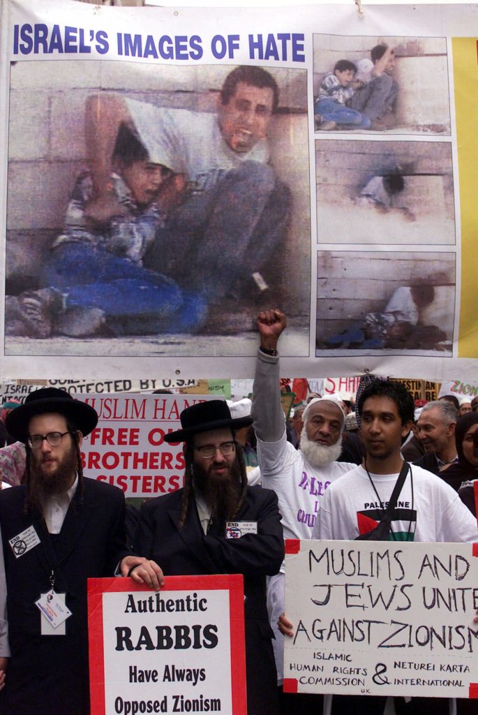 Orthodox Jews and pro-Palestinian supporters participate in a protest march in Durban, South Africa, Friday Aug. 31, 2001 to coincide with the opening of the UN Racism Conference. The series of photographs on the banner show Mohammed Aldura, 12, crouching with his father Jamal Aldura during clashes with Israeli forces in September 2000. Mohammed was fatally shot during the gun battle which was captured on video. (AP Photo/Karel Prinsloo)