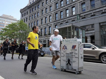 Paul Veneto, right, is joined by Boston Marathon Race Director Dave McGillivray, front left, as Veneto pushes a beverage cart along State Street, in Boston, Saturday, Aug. 21, 2021. Veneto, a former flight attendant who lost several colleagues when United Flight 175 was flown into the World Trade Center on …