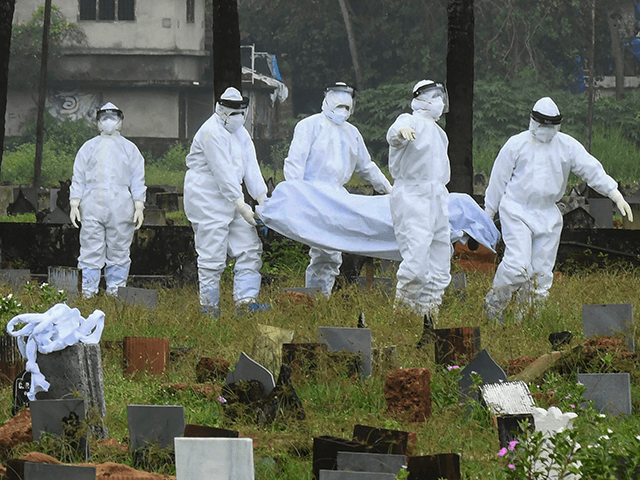 People in protective suits prepare to cremate the body of a 12-year-old boy died of the Ni