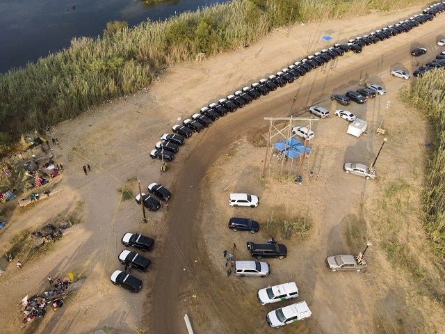 Texas Department of Safety vehicles line up along the bank of the Rio Grande near an encam