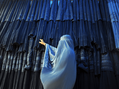 A woman clad in a burqa looks at other pieces of Afghanistan's traditional, all-encompassing dress at a store in Mazar-i Sharif, north of Kabul, Afghanistan, Thursday, Sept. 10, 2015. (AP Photo/Mustafa Najafizada)