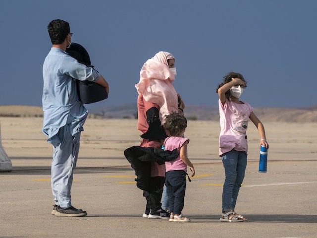 An Afghan family wait on the runway after disembarking a plane from Afghanistan, at the To