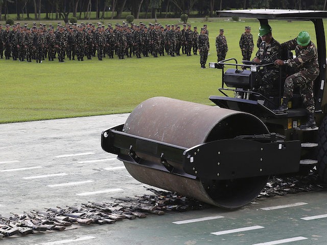 Soldiers uses a bulldozer to run over hundreds of guns and weapons captured, confiscated,