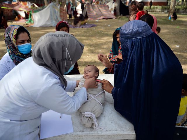 Medical staff check the children of a burqa-clad women during a free medical camp for internally displaced people at Shahr-e-Naw Park in Kabul on September 11, 2021. (Hoshang Hashimi/AFP via Getty Images)