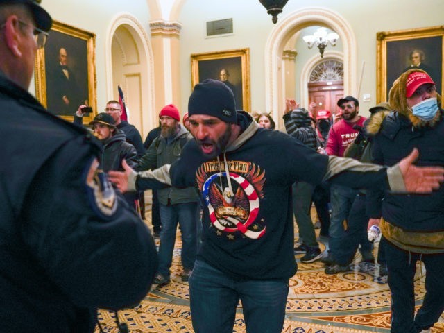 In this Jan. 6, 2021, file photo, Trump supporters, including Doug Jensen, center, confront U.S. Capitol Police in the hallway outside of the Senate chamber at the Capitol in Washington. Some followers of the QAnon conspiracy theory are now turning to online support groups and even therapy to help them …