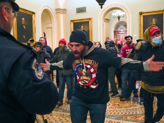 In this Jan. 6, 2021, file photo, Trump supporters, including Doug Jensen, center, confront U.S. Capitol Police in the hallway outside of the Senate chamber at the Capitol in Washington. Some followers of the QAnon conspiracy theory are now turning to online support groups and even therapy to help them move on, now that it's clear Donald Trump's presidency is over. (AP Photo/Manuel Balce Ceneta, File)