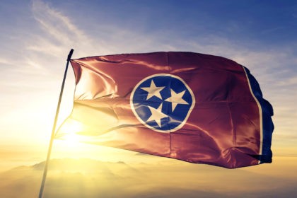 Tennessee state of United States flag on flagpole textile cloth fabric waving on the top sunrise mist fog