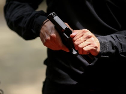 Details with the hands of a man handling a 9 mm handgun