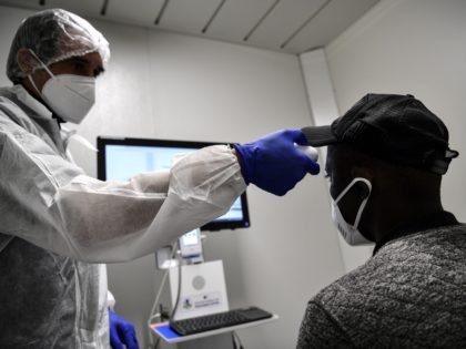 Malian migrant worker Tidjane (R) wearing a protective face mask has his temperature checked ahead of a teleconsultation on suspicion of COVID-19, at a special medical unit set up outside a building housing migrant workers as part of a private initiative supported by the Paris city hall and aimed at …