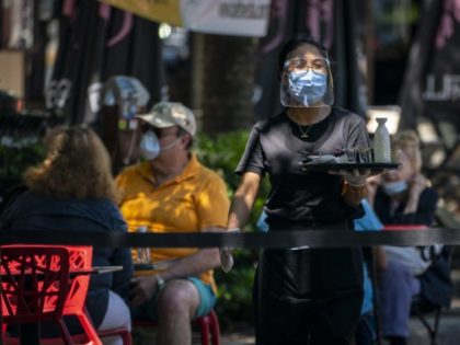 BETHESDA, MD - JUNE 12: A waiter at Raku, an Asian restaurant in Bethesda, wears a protective face mask as serve customers outdoors amid the coronavirus pandemic on June 12, 2020 in Bethesda, Maryland. Many streets are closed to vehicles in downtown Bethesda as Montgomery County continues its phase one …