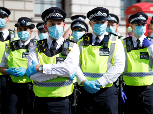 Police officers wearing face masks and gloves due to the COVID-19 pandemic, stand on duty