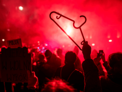 A demonstrator holds up a cloth hanger as others light flares during a pro-choice demonstration in front of the constitutional court in Warsaw, Poland, on January 28, 2021, as part of a nationwide wave of protests since October 22, 2020 against Poland's near-total ban on abortion. - Hundreds of Poles …
