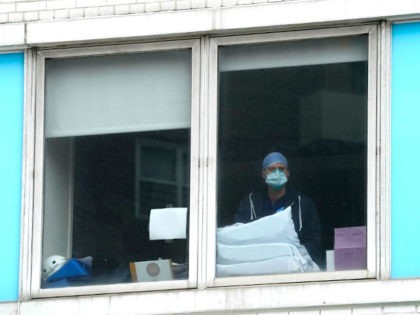 A hospital worker looks out the window as nurses gather outside of Mount Sinai Hospital in Manhattan on March 16, 2021, as they hold a rally demanding that Albany lawmakers pass "Safe Staffing" on what is the one-year anniversary of the Covid-19 lockdown in New York. (Photo by TIMOTHY A. …