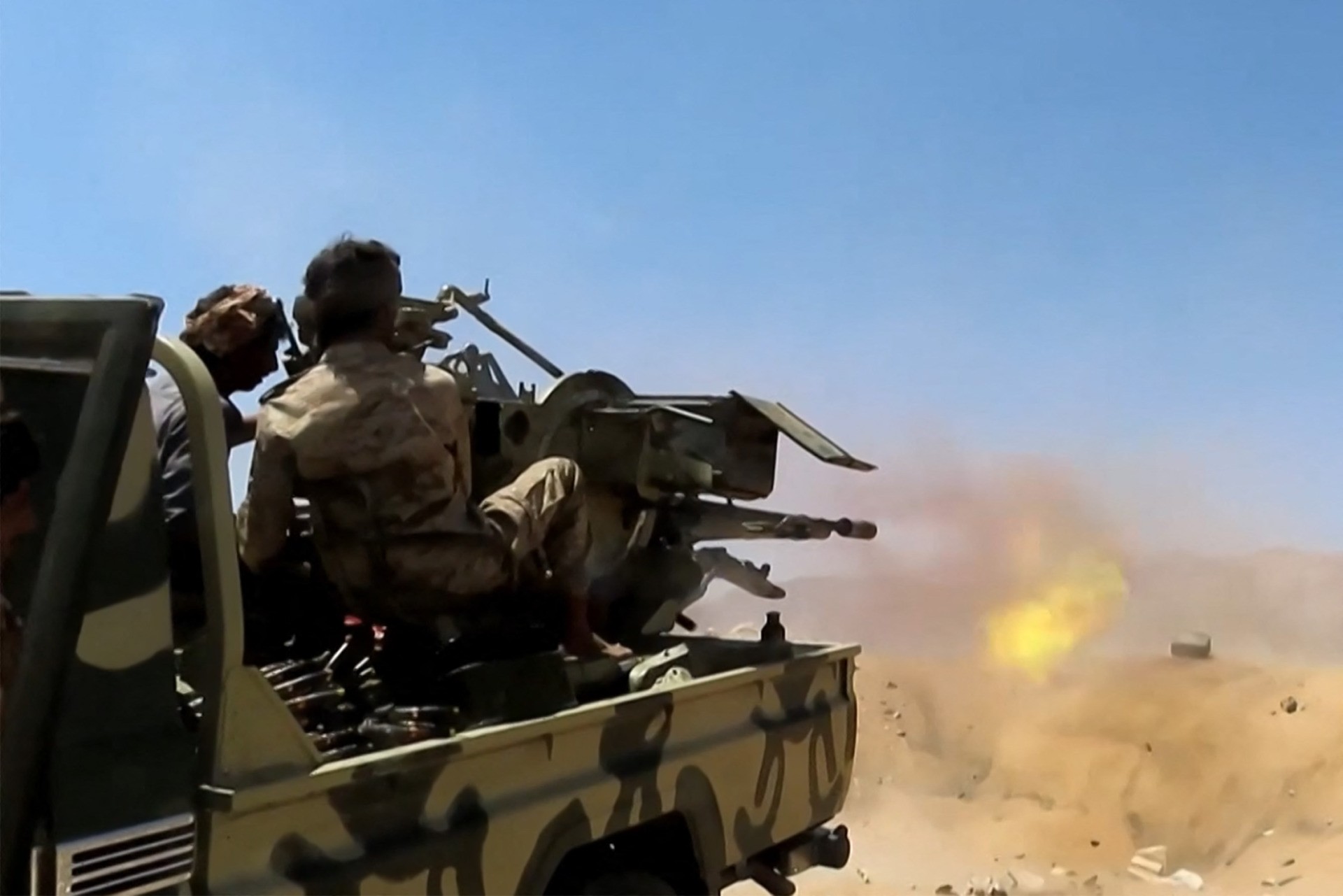 A grab from an AFPTV video shows a fighter loyal to Yemen's Saudi-backed government firing a turret mounted in the back of a pickup truck (technical) at a position near the frontlines against the Huthi rebel forces in the region of al-Kassara, northwest of Marib, on June 28, 2021. - Clashes between rebels and Yemeni government fighters left over a hundred killed in Marib in three days, pro-government sources said, following a renewed offensive by the Iran-allied Huthis who escalated their efforts to seize the government's last stronghold in northern Yemen. (Photo by - / AFPTV / AFP) (Photo by -/AFPTV/AFP via Getty Images)