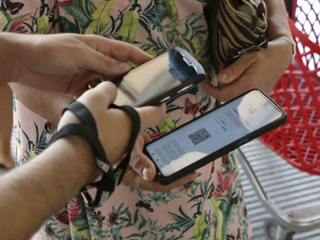 An employee of the Atrium shopping center controls a visitor's QR code health pass in Ajaccio, south Corsica, on August 16, 2021. - A health pass is now mandatory in France to access most of the public spaces or to travel on intercity trains following the Government's plan to squeeze …