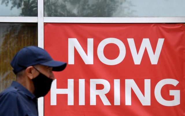 A man walks by a "Now Hiring" sign outside a store on August 16, 2021 in Arlingt