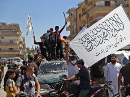 TOPSHOT - Members of Syria's top jihadist group the Hayat Tahrir al-Sham (HTS) alliance, led by al-Qaeda's former Syria affiliate, parade with their flags and those of the Taliban's declared "Islamic Emirate of Afghanistan" through the rebel-held northwestern city of Idlib on August 20, 2021. - The armed group that …