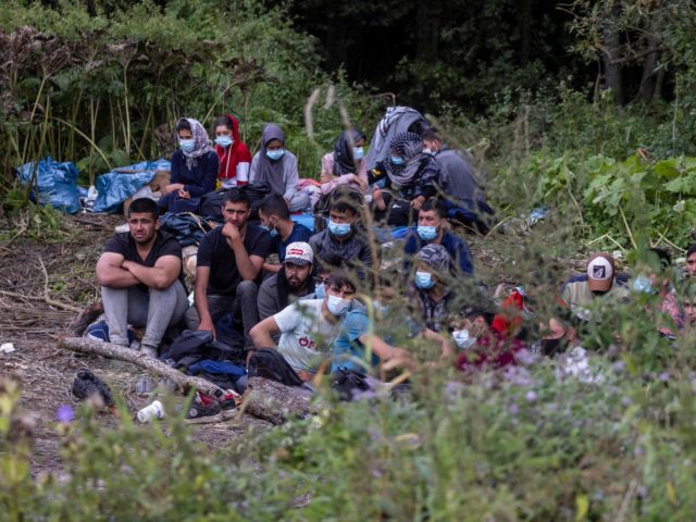 Migrants believed to be from Afghanistan sit on the ground in the small vilage of Usnarz G