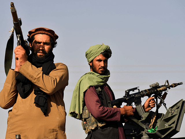 Taliban fighters stand on an armoured vehicle before parading along a road to celebrate af
