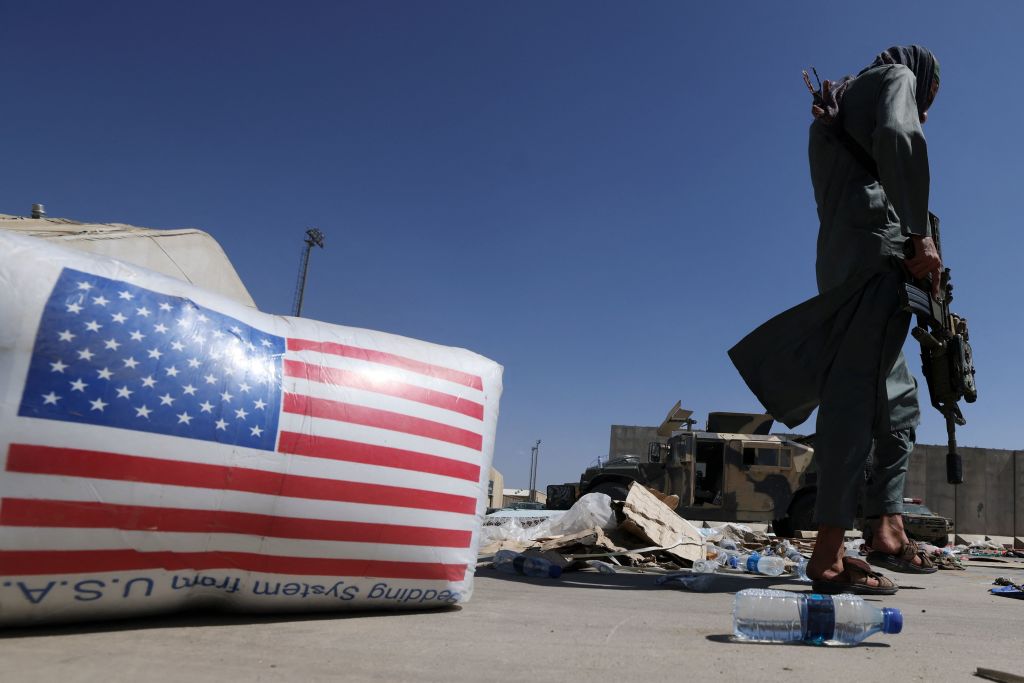 A Taliban fighter walks past a US national flag at the airport in Kabul on September 14, 2021. (Photo by Karim SAHIB / AFP) (Photo by KARIM SAHIB/AFP via Getty Images)