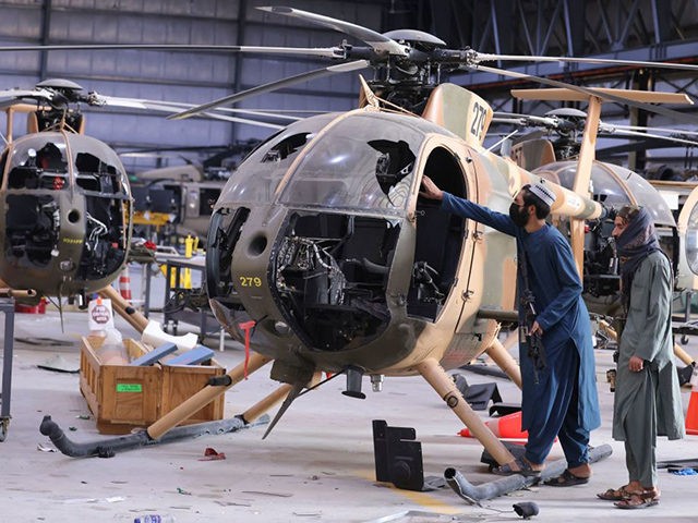 Taliban fighters check the cockpit of a damaged Afghan Air Force helicopter at a hangar at the airport in Kabul on September 14, 2021. (Karim Sahib/AFP via Getty Images)