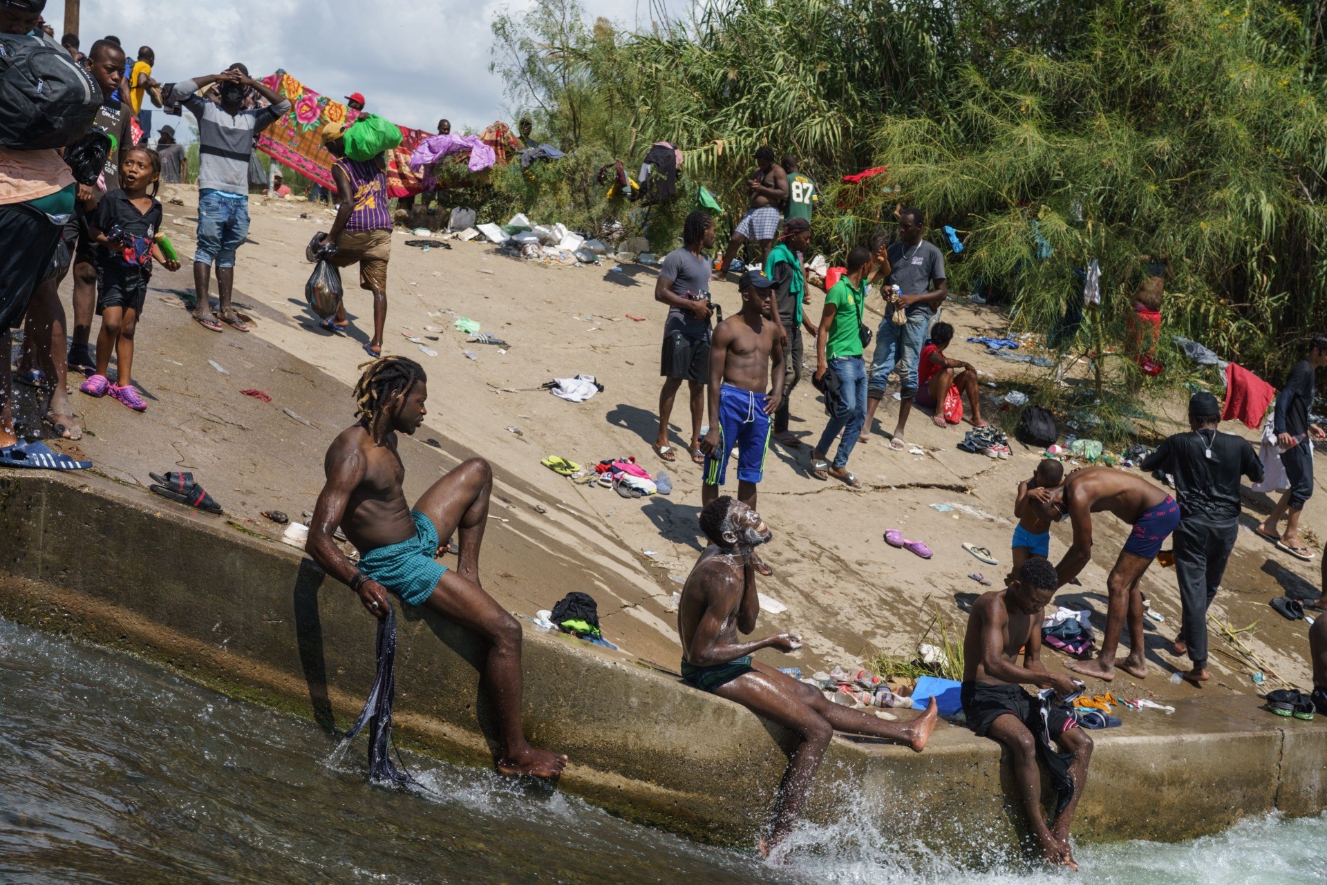 Migrant men bathe in the Rio Grande near the Del Rio-Acuna Port of Entry in Del Rio, Texas, on September 18, 2021. - The United States said on September 18 that it would ramp up deportation flights for thousands of migrants who flooded into the Texas border city of Del Rio, as authorities scramble to alleviate a burgeoning crisis for President Joe Biden's administration. The migrants who poured into the city, many of them Haitian, were being held in an area controlled by US Customs and Border Protection (CBP) beneath the Del Rio International Bridge, which carries traffic across the Rio Grande river into Mexico. (Photo by PAUL RATJE / AFP) (Photo by PAUL RATJE/AFP via Getty Images)