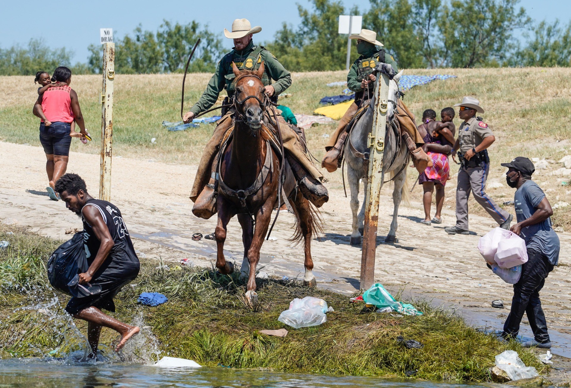 TOPSHOT - United States Border Patrol agents on horseback try to stop Haitian migrants from entering an encampment on the banks of the Rio Grande near the Acuna Del Rio International Bridge in Del Rio, Texas on September 19, 2021. - US law enforcement are attempting to close off crossing points along the Rio Grande river where migrants cross to get food and water, which is scarce in the encampment. The United States said Saturday it would ramp up deportation flights for thousands of migrants who flooded into the Texas border city of Del Rio, as authorities scramble to alleviate a burgeoning crisis for President Joe Biden's administration. (Photo by PAUL RATJE / AFP) (Photo by PAUL RATJE/AFP via Getty Images)