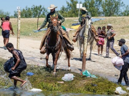 TOPSHOT - United States Border Patrol agents on horseback try to stop Haitian migrants fro