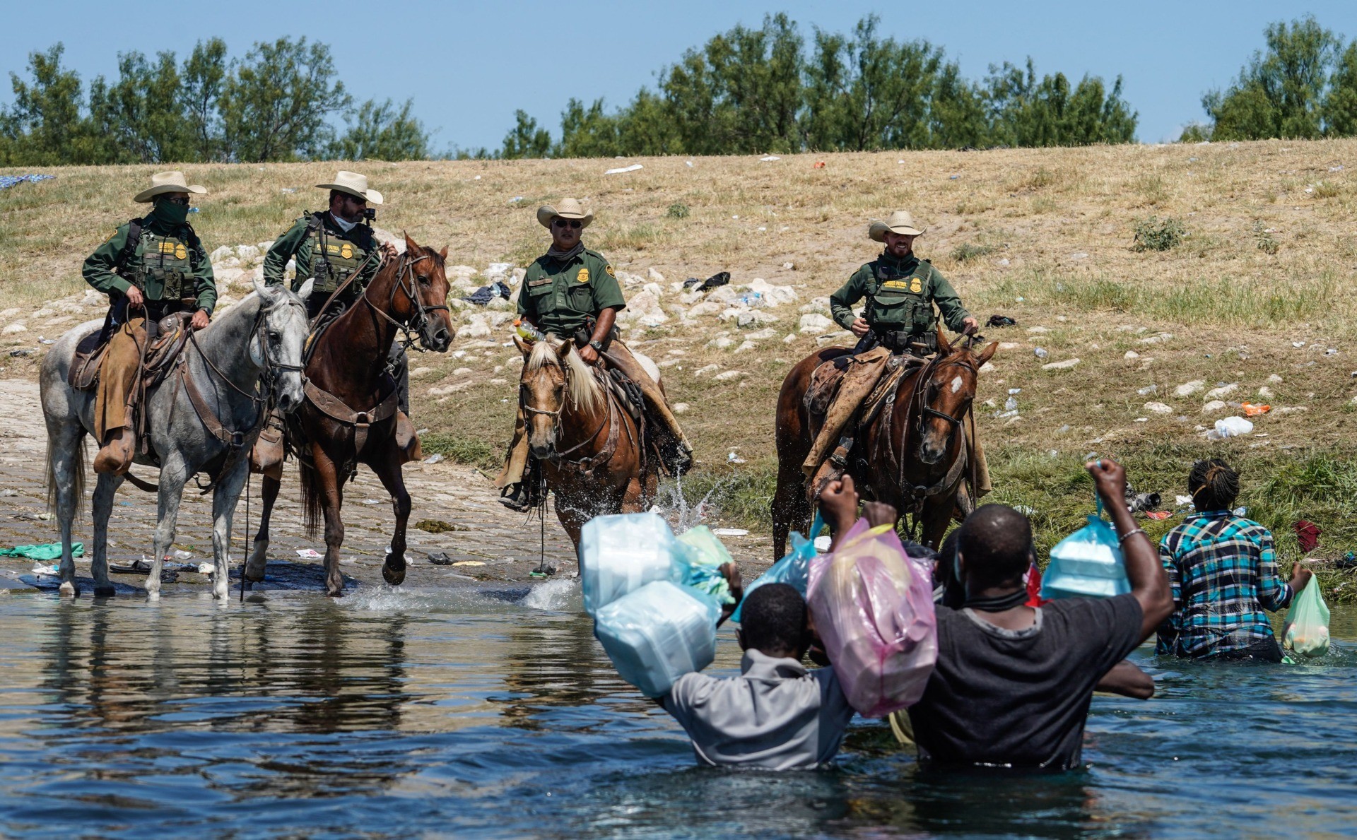 United States Border Patrol agents on horseback try to stop Haitian migrants from entering an encampment on the banks of the Rio Grande near the Acuna Del Rio International Bridge in Del Rio, Texas on September 19, 2021. - US law enforcement are attempting to close off crossing points along the Rio Grande river where migrants cross to get food and water, which is scarce in the encampment. The United States said Saturday it would ramp up deportation flights for thousands of migrants who flooded into the Texas border city of Del Rio, as authorities scramble to alleviate a burgeoning crisis for President Joe Biden's administration. (Photo by PAUL RATJE / AFP) (Photo by PAUL RATJE/AFP via Getty Images)
