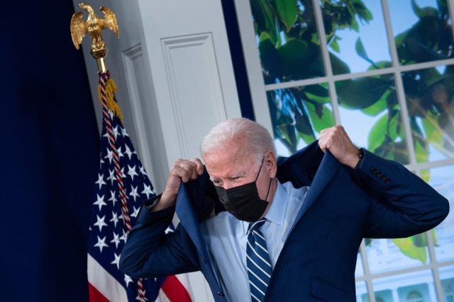 US President Joe Biden puts on his suit jacket after receiving a third shot of the Pfizer