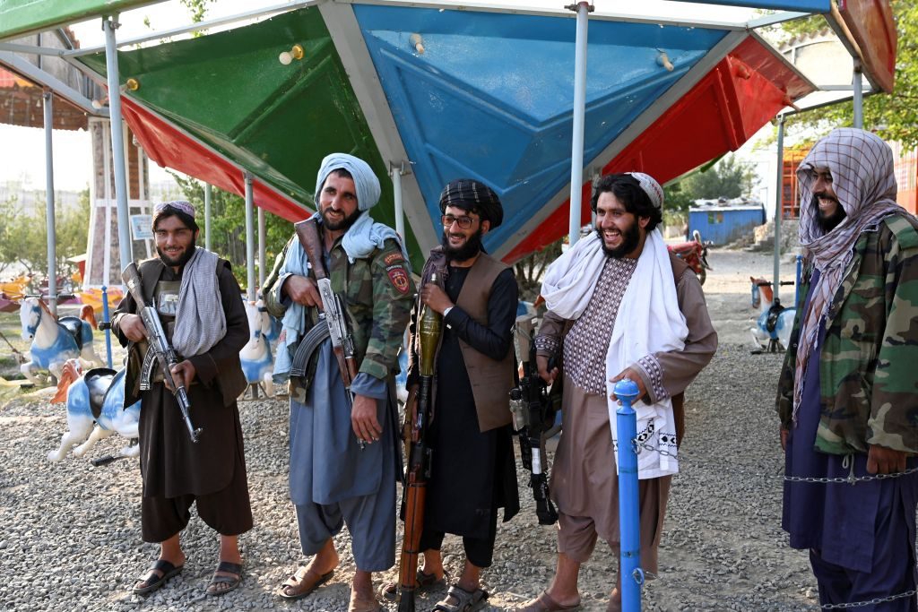In this photograph taken on September 28, 2021 Taliban fighters stand next to a merry-go-around ride in a fairground at Qargha Lake on the outskirts of Kabul. - "This is Afghanistan!" a Taliban fighter shouts on the pirate ship ride at a fairground in western Kabul, as his armed comrades cackle and whoop on board the rickety attraction. - TO GO WITH: Afghanistan-conflict-fairground, SCENE by James EDGAR (Photo by WAKIL KOHSAR / AFP) / TO GO WITH: Afghanistan-conflict-fairground, SCENE by James EDGAR (Photo by WAKIL KOHSAR/AFP via Getty Images)