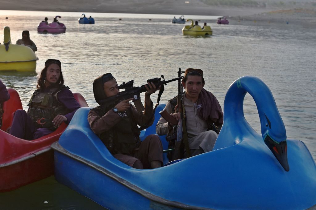 TOPSHOT - In this photograph taken on September 28, 2021 Taliban fighters ride on paddle boats at Qargha Lake on the outskirts of Kabul. - "This is Afghanistan!" a Taliban fighter shouts on the pirate ship ride at a fairground in western Kabul, as his armed comrades cackle and whoop on board the rickety attraction. - TO GO WITH: Afghanistan-conflict-fairground, SCENE by James EDGAR (Photo by WAKIL KOHSAR / AFP) / TO GO WITH: Afghanistan-conflict-fairground, SCENE by James EDGAR (Photo by WAKIL KOHSAR/AFP via Getty Images)
