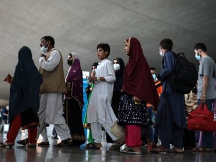 DULLES, VIRGINIA - AUGUST 31: Refugees walk through the departure terminal to a bus at Dulles International Airport after being evacuated from Kabul following the Taliban takeover of Afghanistan on August 31, 2021 in Dulles, Virginia. The Department of Defense announced yesterday that the U.S. military had completed its withdrawal …