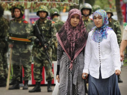 Two ethnic Uighur women pass Chinese paramilitary policemen standing guard outside the Gra