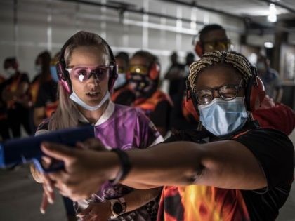 With the help of an instructor (L) and of a mock pistol a South African woman learns to control her weapon while others gather at the lower end of a shooting range as they take part in a training organised by the women empowerment group Girls on Fire, in Midrand, …
