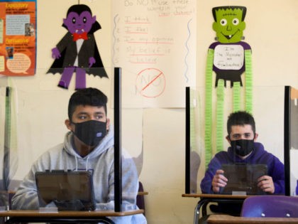 Students sit behind barriers and use tablets during an in-person English class at St. Anthony Catholic High School during the Covid-19 pandemic on March 24, 2021 in Long Beach, California. - The school of 445 students implemented a hybrid learning model, with approximately 60 percent of students returning to in …