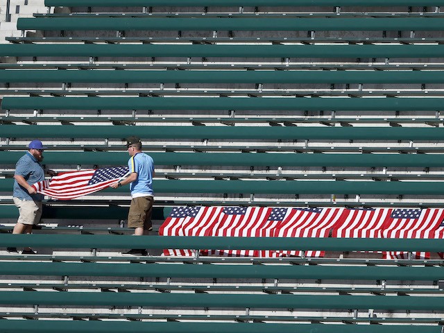 SEATTLE, WASHINGTON - SEPTEMBER 01: Fans fold flags to honor 13 US service members killed in Kabul airport attack after the game between the Seattle Mariners and the Houston Astros at T-Mobile Park on September 01, 2021 in Seattle, Washington. (Photo by Steph Chambers/Getty Images)