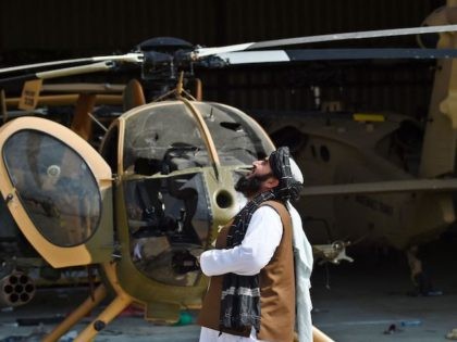 A Taliban member looks up standing next to a damaged helicopter at the airport in Kabul on August 31, 2021, after the US has pulled all its troops out of the country to end a brutal 20-year war -- one that started and ended with the hardline Islamist in power. &hellip;