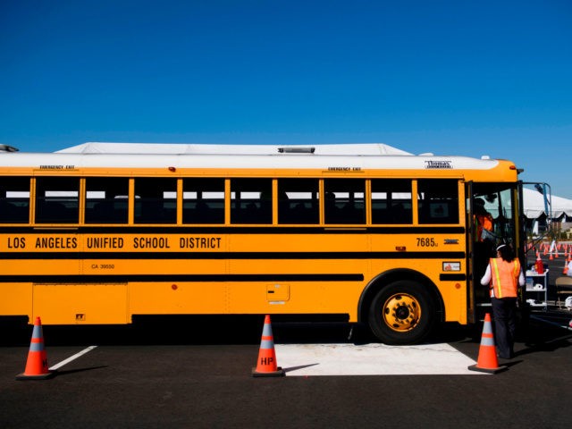 Vaccination site workers board a school bus transporting education workers as it arrives at a mass vaccination site in a parking lot at Hollywood Park adjacent to SoFi stadium during the Covid-19 pandemic on March 1, 2021 in Inglewood, California. - The vaccination site is part of a plan from …