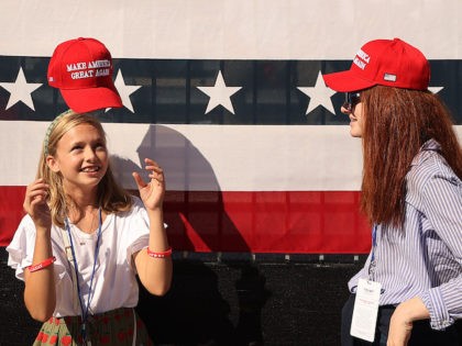 A girl tosses her Make America Great Again hat onto her head while waiting for the start of a campaign rally with U.S. President Donald Trump at Phoenix Goodyear Airport October 28, 2020 in Goodyear, Arizona. (Chip Somodevilla/Getty Images)