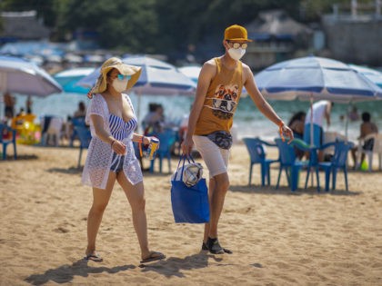 ACAPULCO, MEXICO - MARCH 19: Tourists wearing a mask walk along Caleta beach on March 19, 2021 in Acapulco, Mexico. Acapulco began its vaccination plan for senior citizens on March 17, people over 60 years old will receive the first dose of the vaccine against Covid-19. Acapulco remains as one …