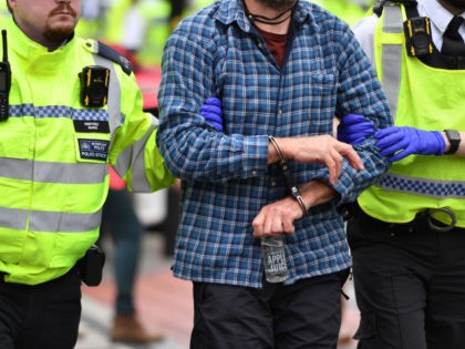 Police officers detain and escort away a climate activist from the Extinction Rebellion gr